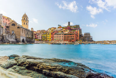 View of buildings by sea against sky in city