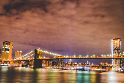 Illuminated bridge over river at night