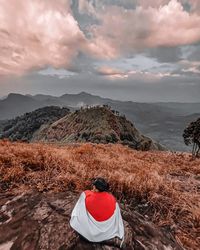 Rear view of person on mountain against sky during sunset