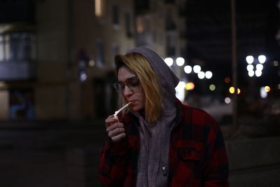 Young woman holding ice cream cone at night