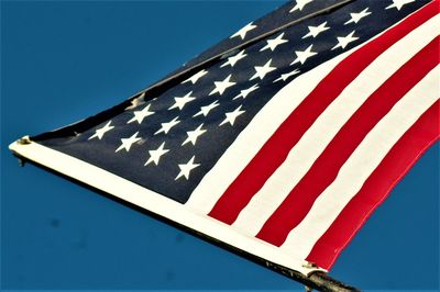 Low angle view of flag against blue sky