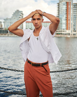 Portrait of young man standing against buildings in city