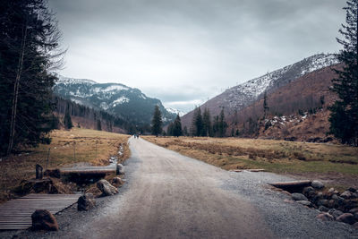 Road amidst snowcapped mountains against sky. koscielska valley, tatra mountains, poland