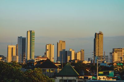 Buildings in city against clear sky during sunset