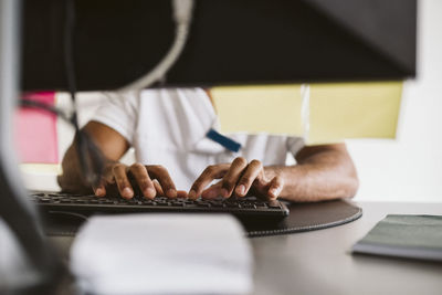 Midsection of male doctor typing while working at medical clinic