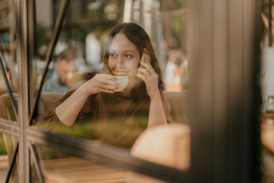 Portrait of young woman looking at camera reflection