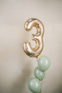 A composition of helium balloons of green color, as well as a large figure of three golden colors.