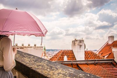 Woman holding umbrella and standing at balcony