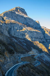 Scenic view of mountain road against clear blue sky