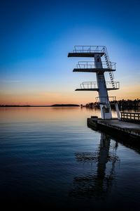 Silhouette pier by lake against sky during sunset