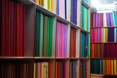 Multi colored fabrics arranged on shelves at shop