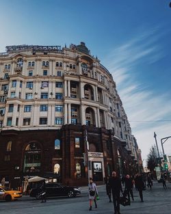People on street by building against sky in city