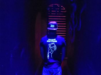 Rear view of person standing at illuminated nightclub