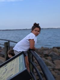 Boy standing on beach against sky