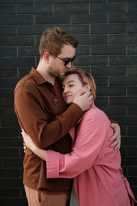 Couple hugging over dark wall. happy man and woman touching tender each other. love and romance