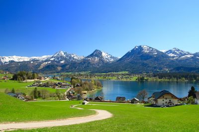 Scenic view of lake and mountains against clear blue sky