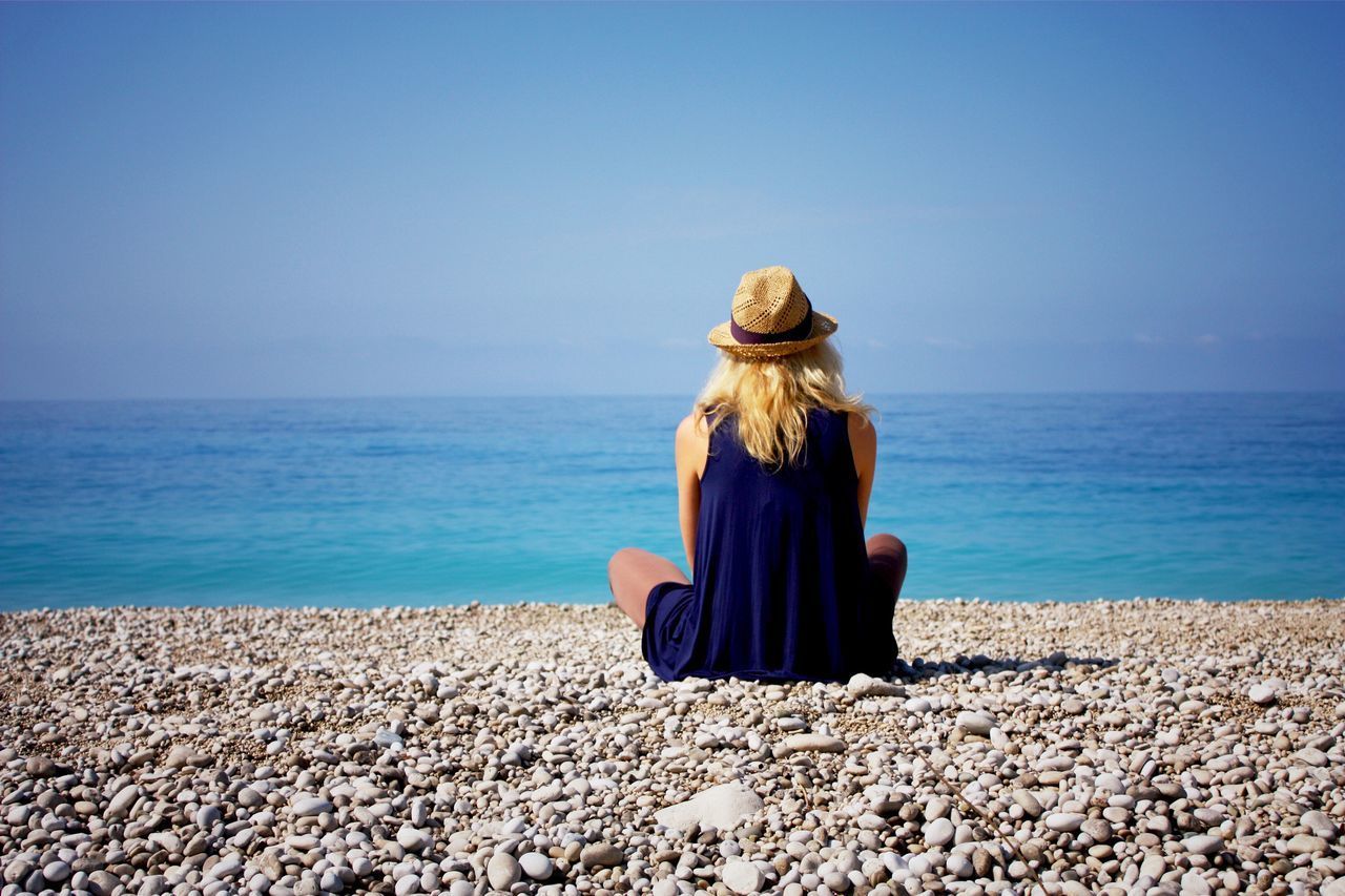 Rear view of woman sitting on beach