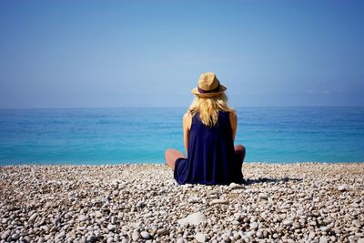 Rear view of woman sitting on beach