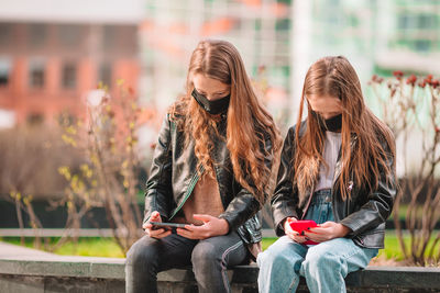 Full length of young woman using mobile phone outdoors