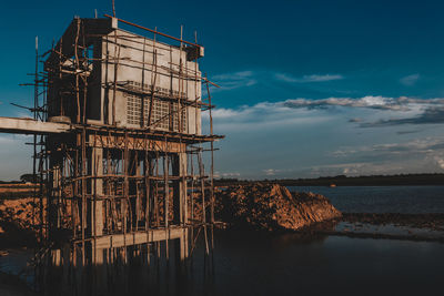 View of factory by sea against sky