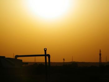 Silhouette built structure against orange sky