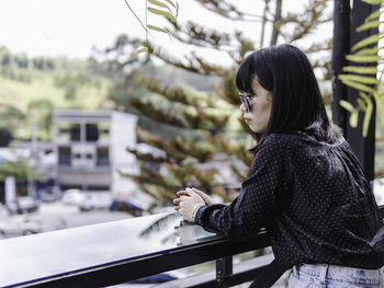 Woman in sunglasses sitting by railing in city