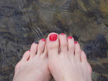 Low section of woman with painted toenails over lake