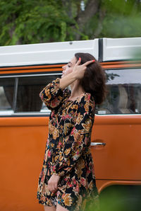 Woman standing against car on road