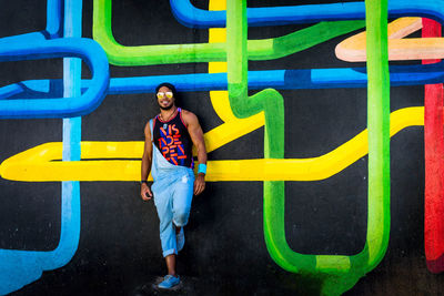 Full length of woman standing against multi colored wall