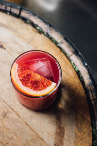 Blood orange cocktail in rocks glass on whiskey barrel