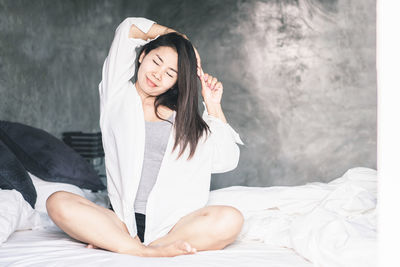 Beautiful young woman sitting on bed