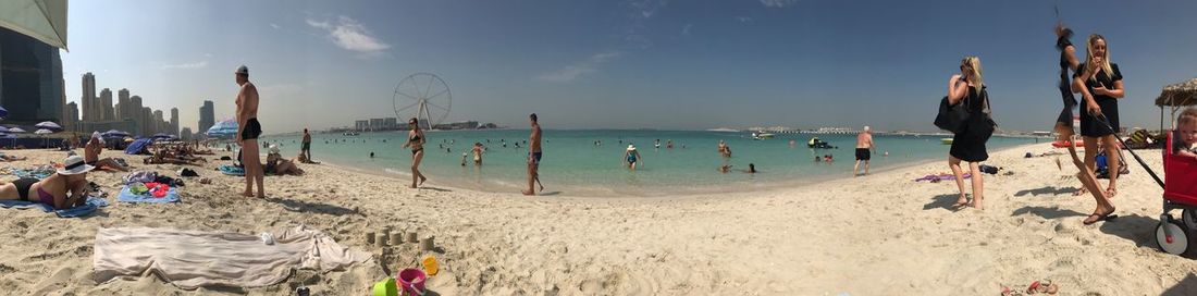 Panoramic view of people on beach against sky