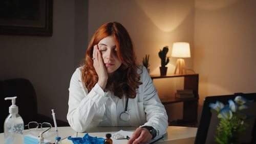 Young female doctor sleeps on the hospital desk tired of the shift