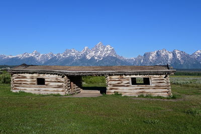 Old structure in front of the grand tetons on a sunny day
