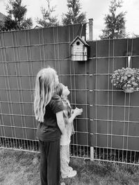 Girl standing by fence against plants