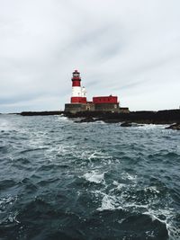 Lighthouse by sea against sky