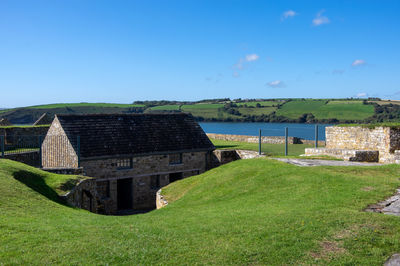 Built structure on grassy field against blue sky