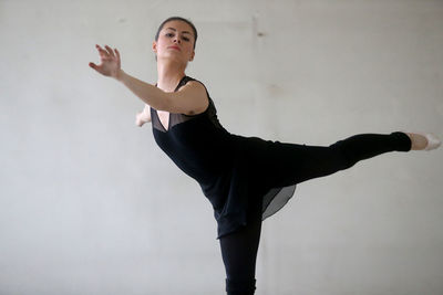 Portrait of young woman doing ballet dance against white background