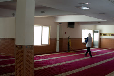Rear view of woman walking in corridor of building