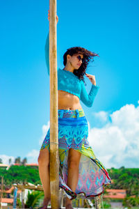 Woman wearing hat standing against blue sky