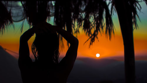 Silhouette woman against sun during sunset