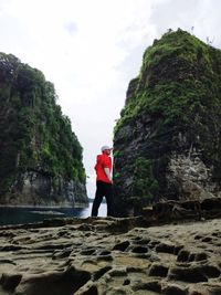 Man standing on rock against sky