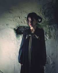 Portrait of woman standing against wall