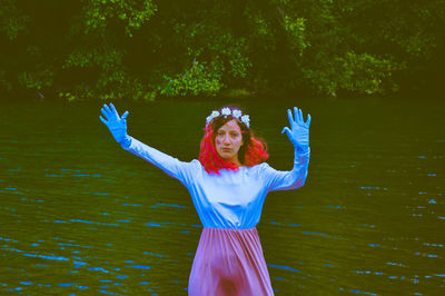 Woman with arms raised standing against trees