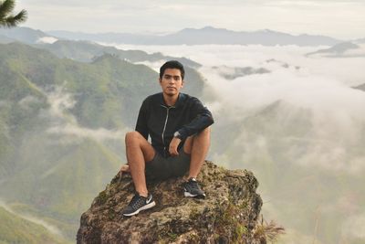 Young man standing on rock against mountains