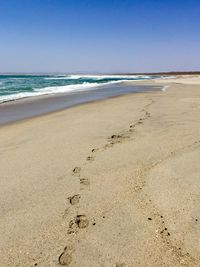 Scenic view of beach against clear blue sky