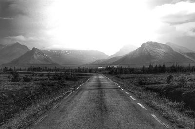 Road by mountains against sky