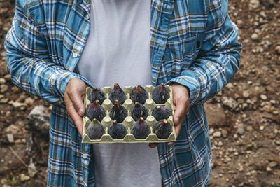 Midsection of man holding figs on plate