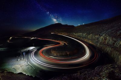 Light trails on road against sky at night