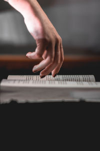 Cropped hand of woman with book on table